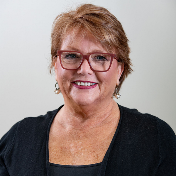 A man in a suit and tie is standing in front of a white background.