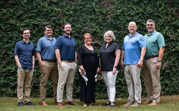 A large group of people are posing for a picture under a tree.