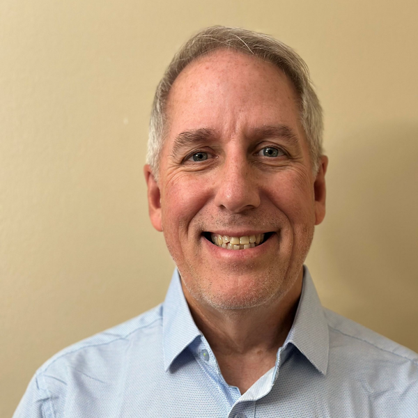 A man in a suit and tie is smiling for the camera.
