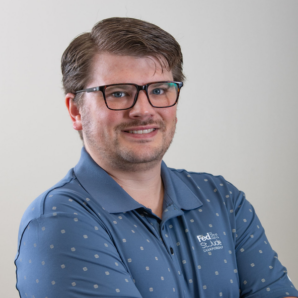 A man in a suit and tie is standing in front of a white background.