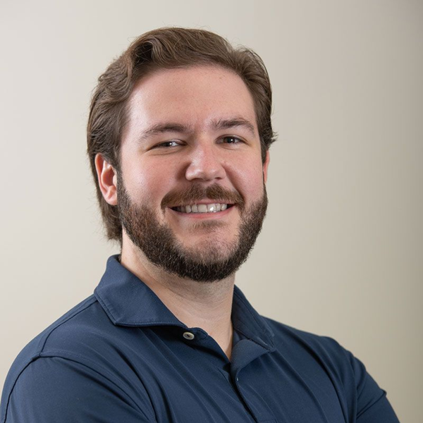 A man in a suit and tie is standing in front of a white background.