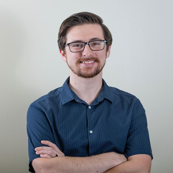 A man in a suit and tie is standing in front of a white background.