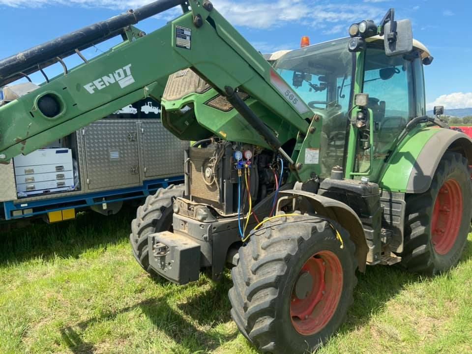 A Green and Red Tractor is Parked in a Grassy Field — Auto Electrician Quirindi