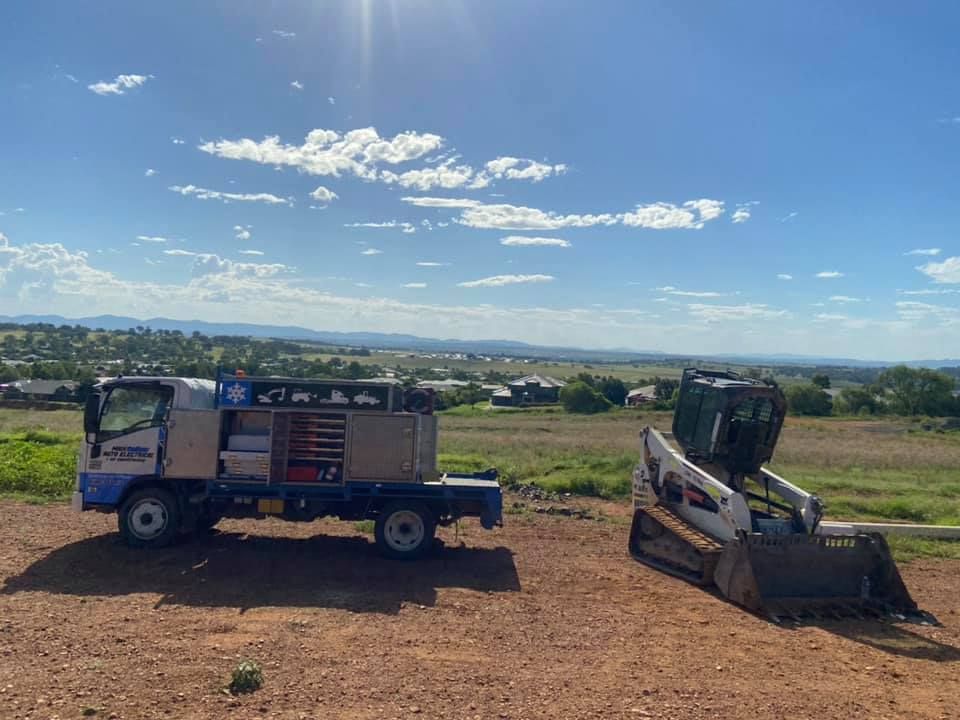 A Bulldozer is Parked next to a truck in a Dirt Field — Auto Electrician Quirindi