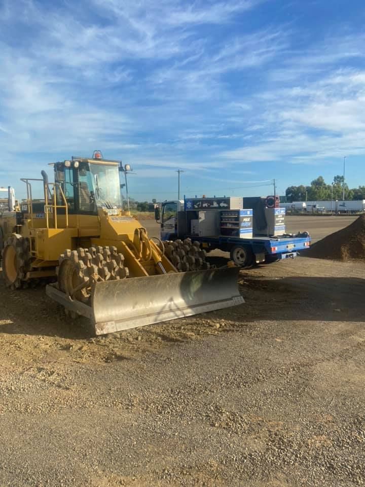 A Bulldozer is Parked in a Gravel lot next to a Truck — Auto Electrician Armidale