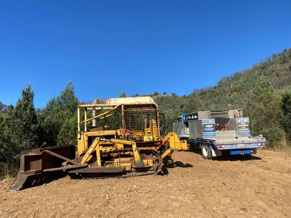 A Bulldozer is Parked Next to a Trailer in a Dirt Field — Mobile Auto Electrician New England