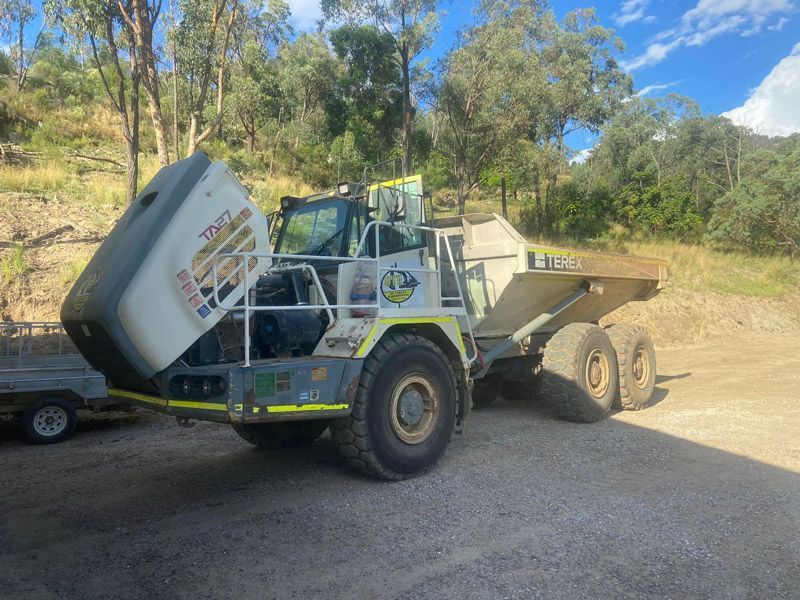 A Dump Truck is Parked in a Gravel Lot Next to a Trailer — Auto Electrical Service Tamworth