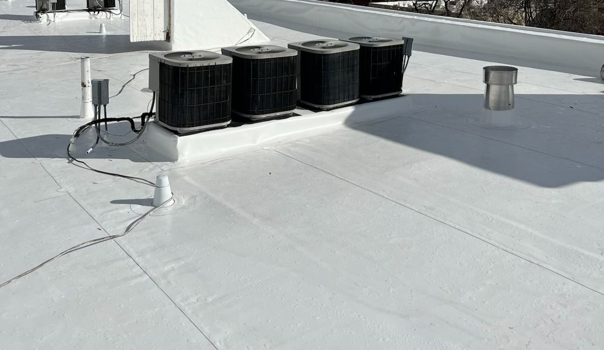 White flat roof with AC units, electrical boxes, and pipes.
