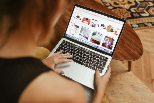 A woman is sitting on a couch using a laptop computer.