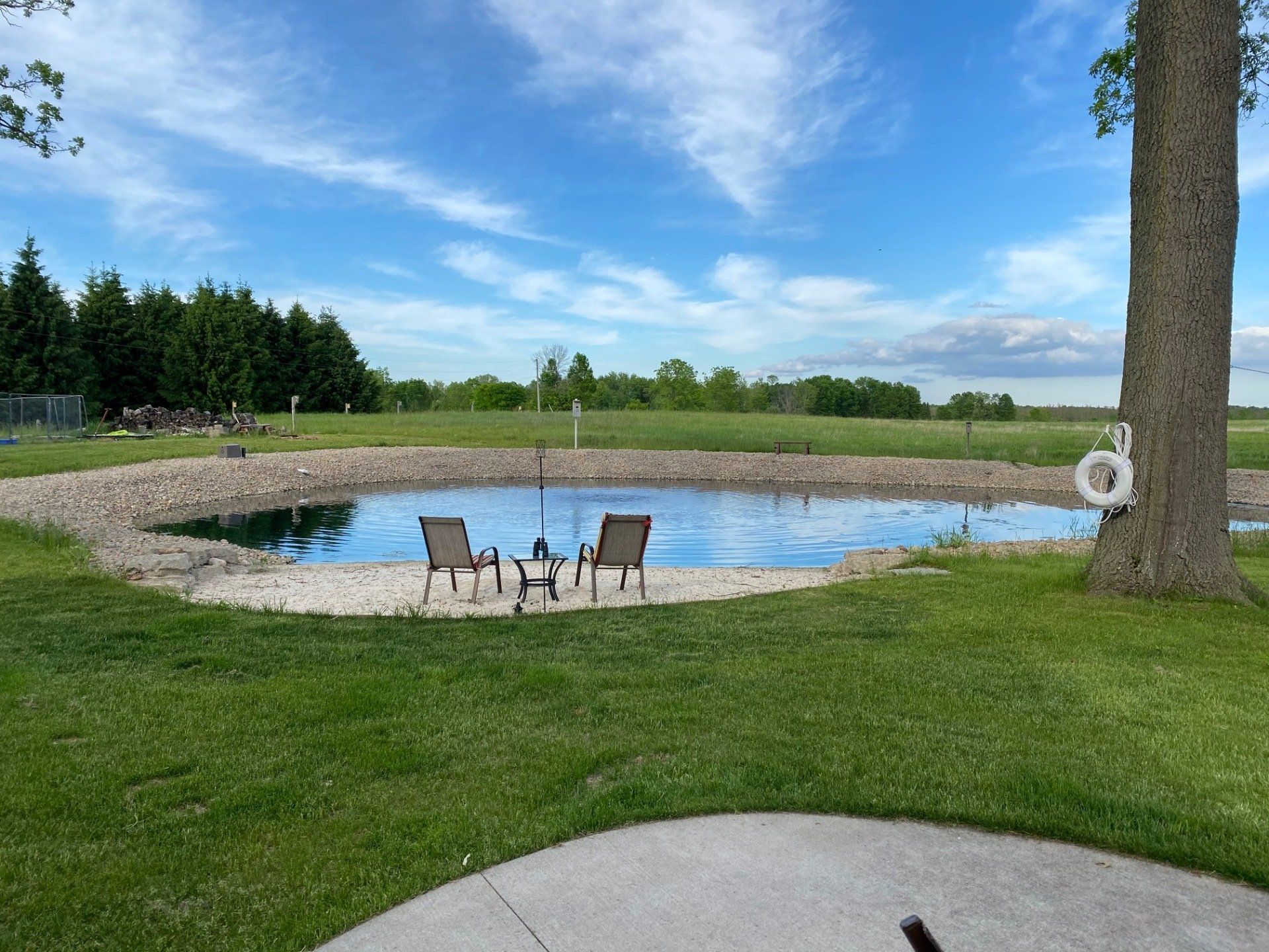 A pond with two chairs and a table in the middle of it.