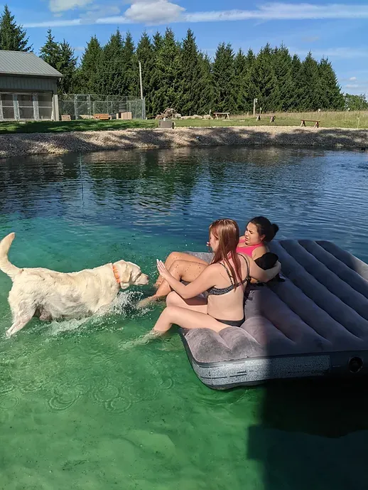 Two women and a dog are sitting on a raft in the water.