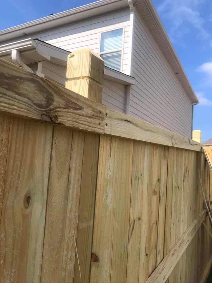 Wooden fence with a house in the background on a sunny day.