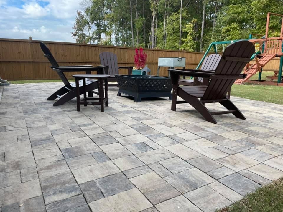 Patio with pavers, dark Adirondack chairs, fire pit, and a wooden fence.
