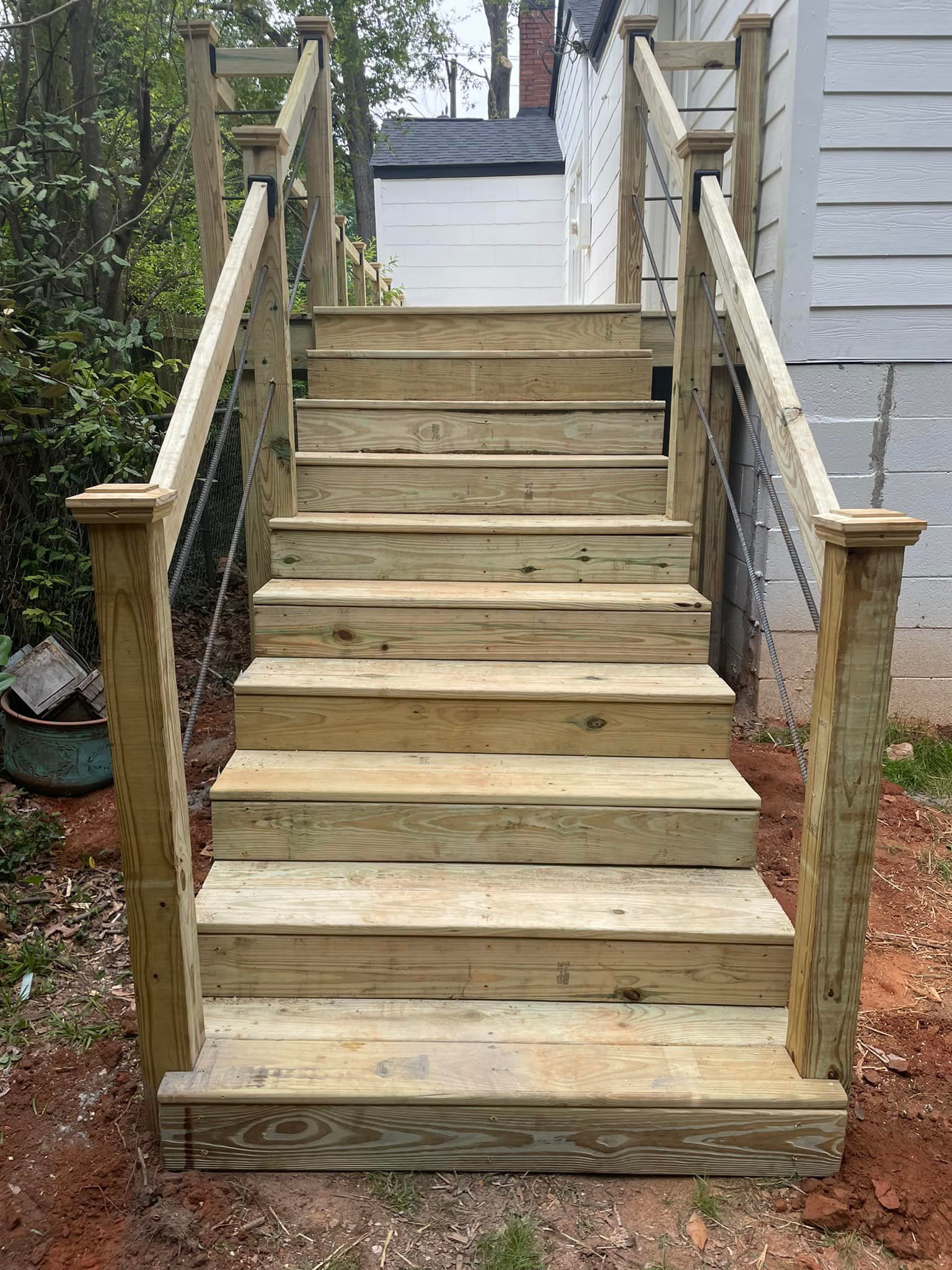 Wooden outdoor stairs with cable railing leading up to a white building.