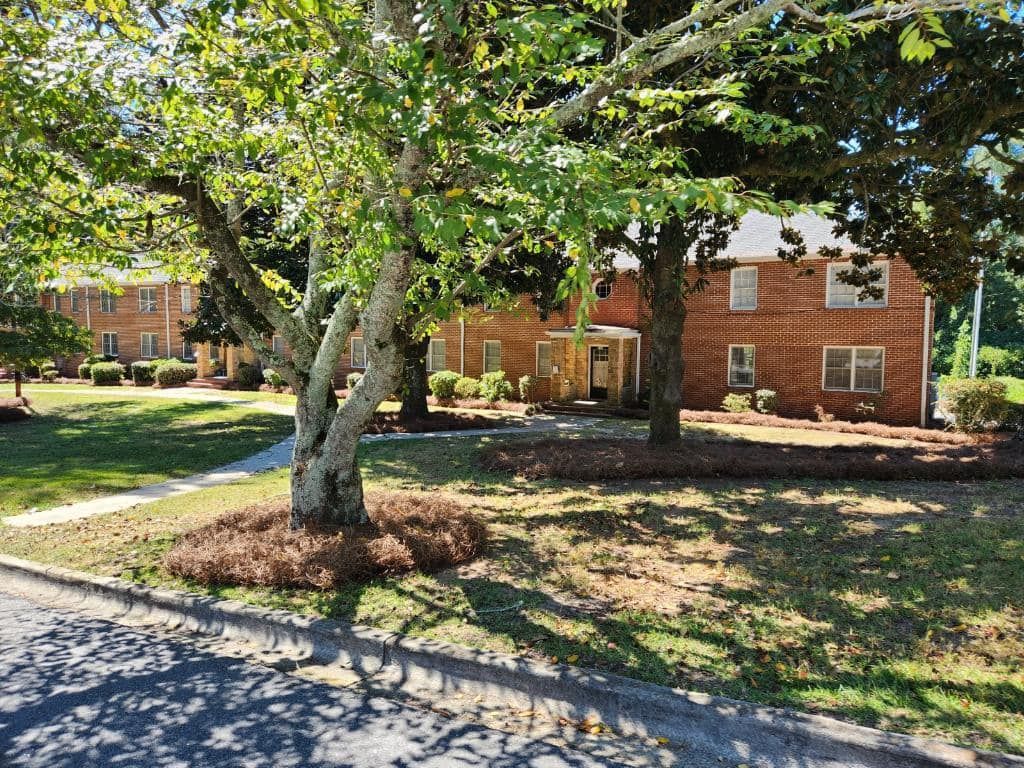 Brick apartment buildings with trees and green grass.