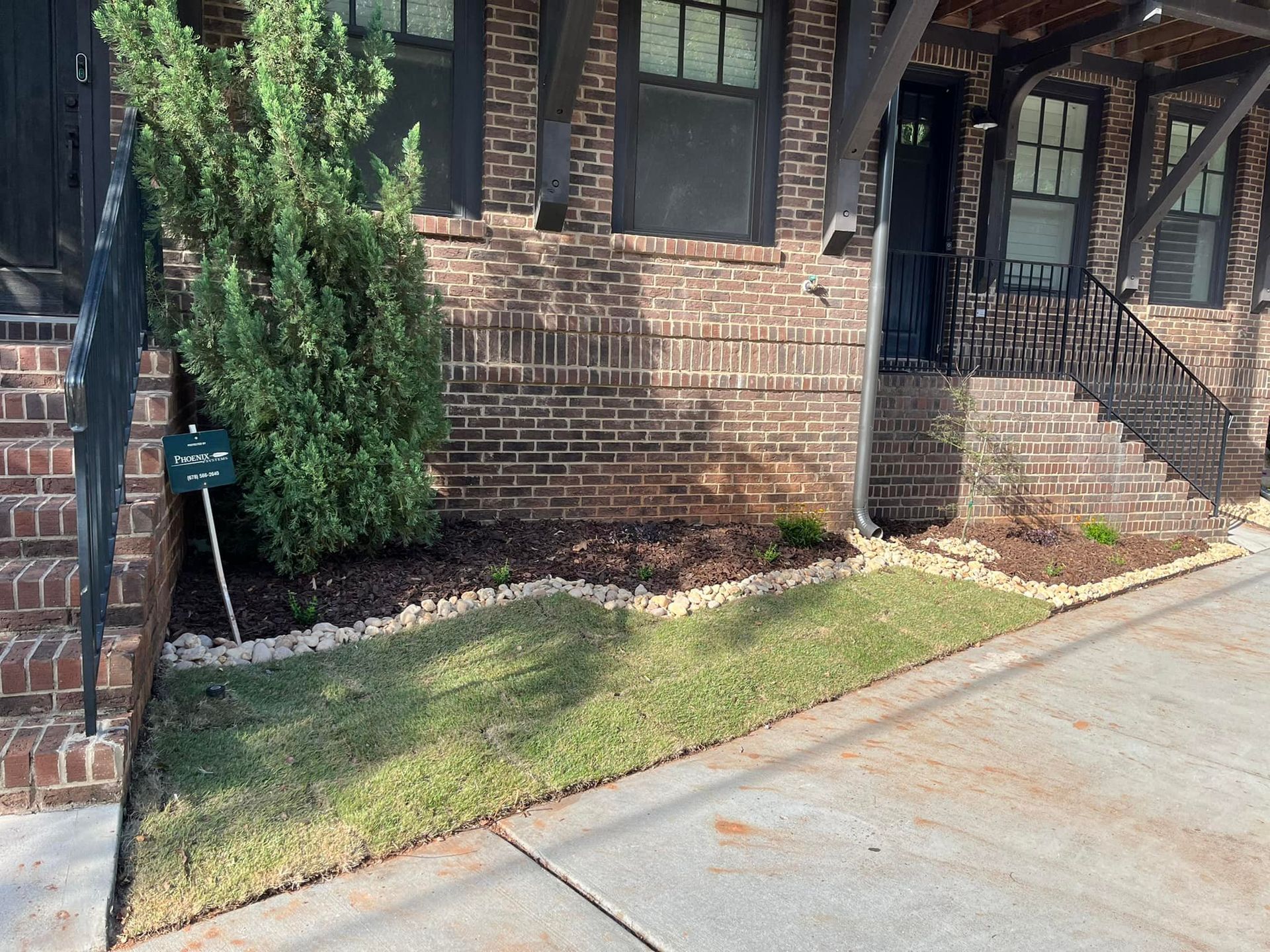 Brick building with a planted bed of grass, mulch and small stones.
