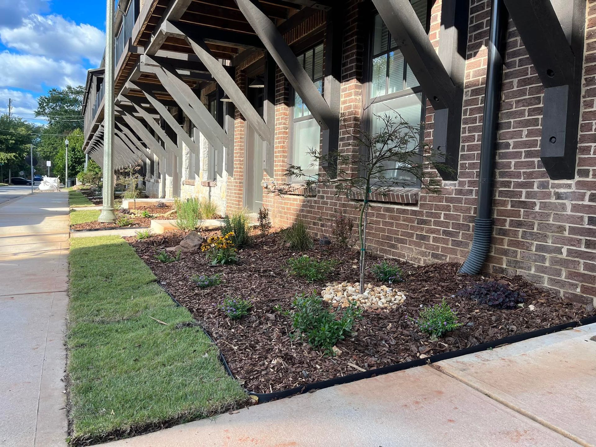 Exterior of building with brick facade, landscaped garden, and awnings.