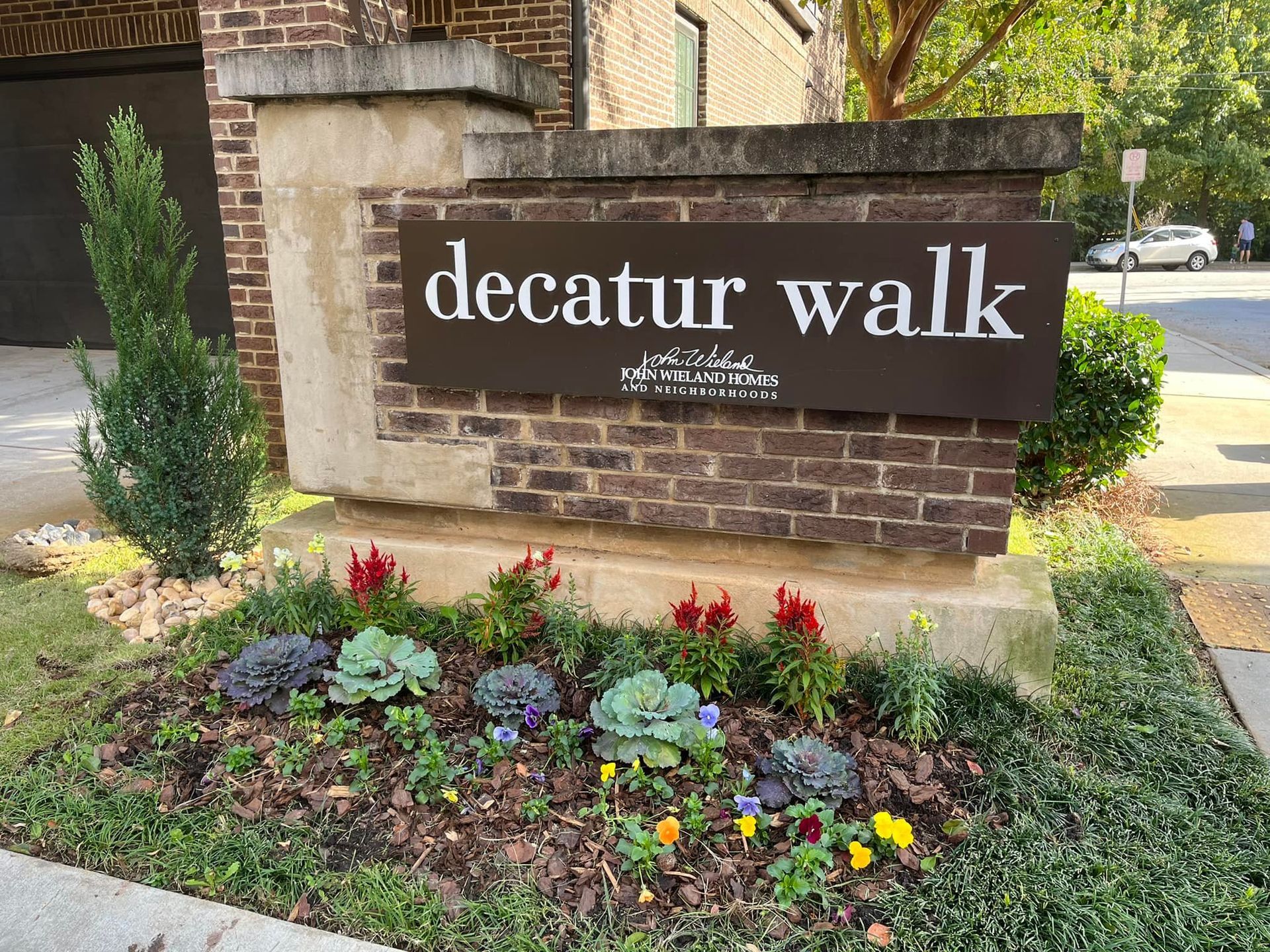 Sign for Decatur Walk apartments with brick and flowerbed.