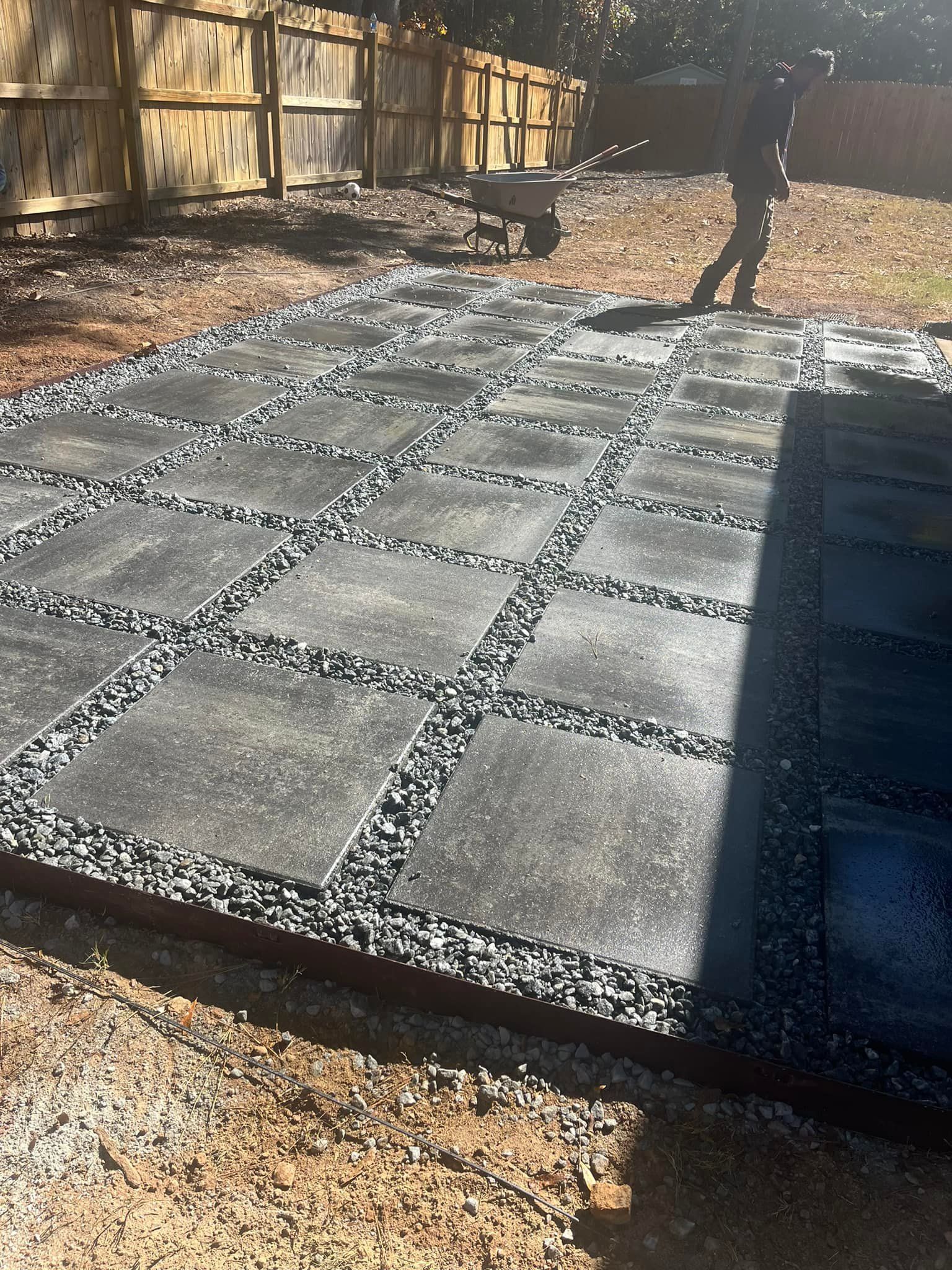 Stone patio with dark grey pavers and gravel between, outdoors.