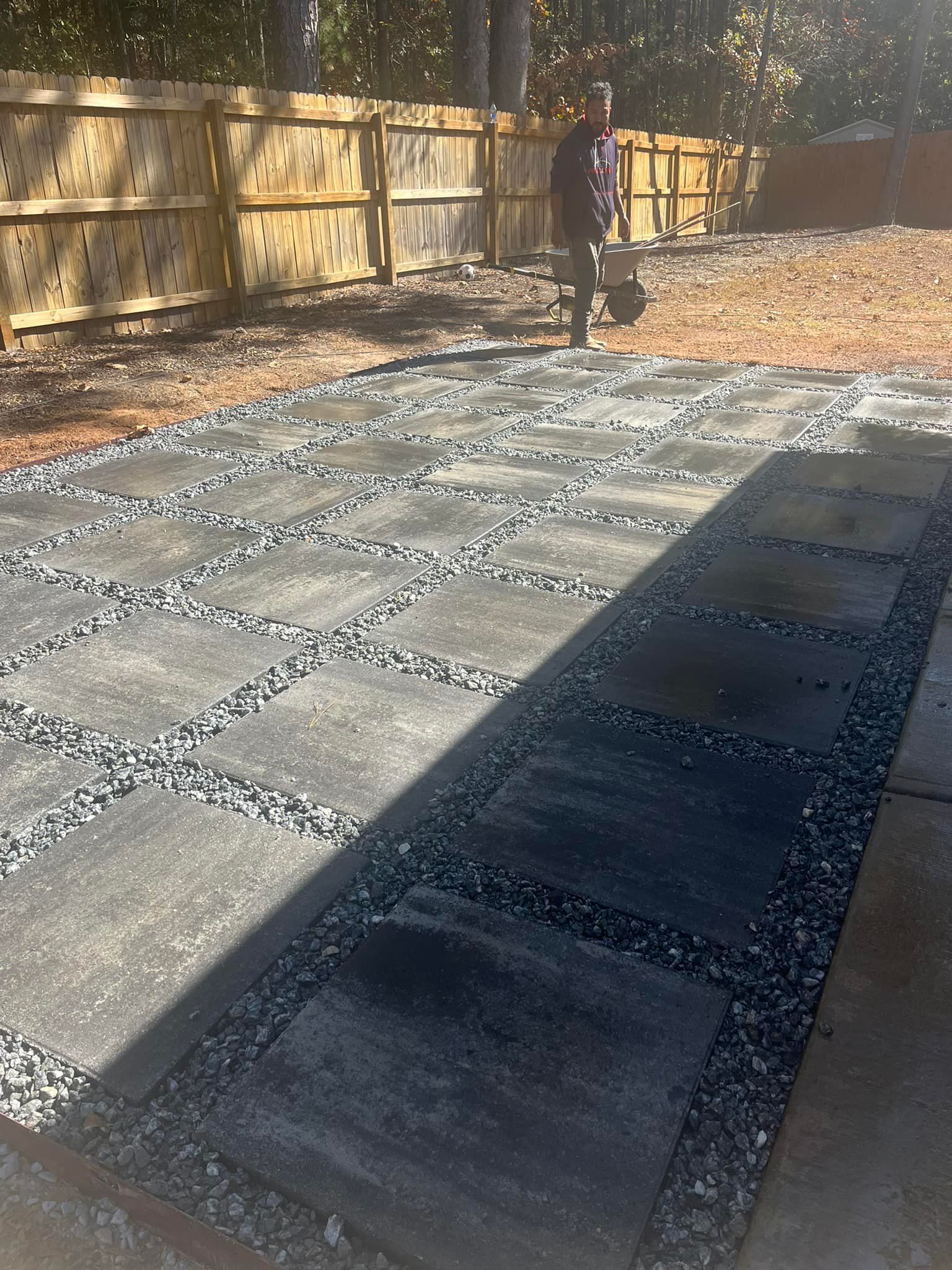Path made of grey pavers and gravel in a backyard, person walking in the background.