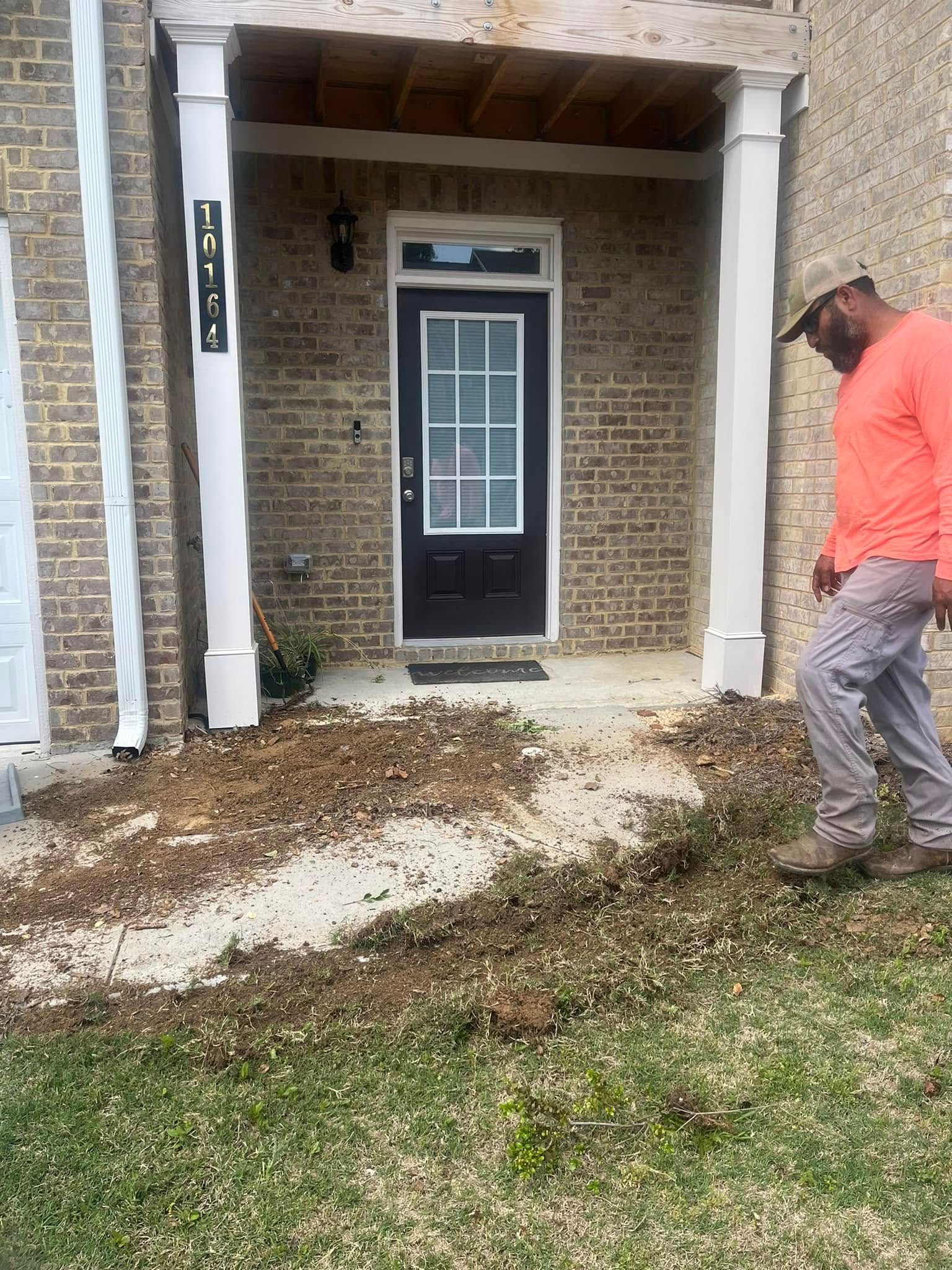 Person working on yard bed in front of a brick building.