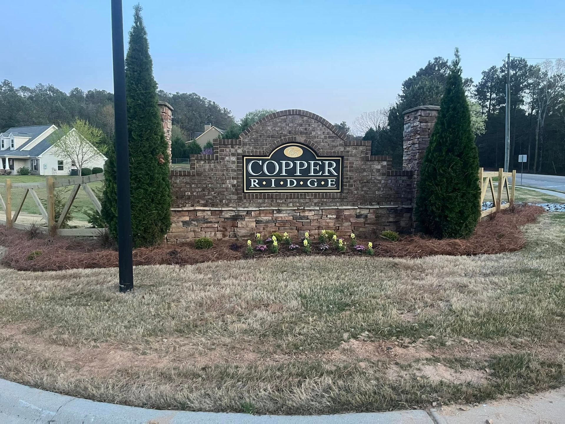 Sign for Copper Ridge residential area, made of brick and stone, flanked by evergreens.