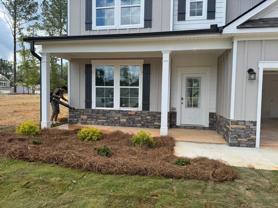A person installs a gutter on a house with stone accents, covered porch, and landscaping.