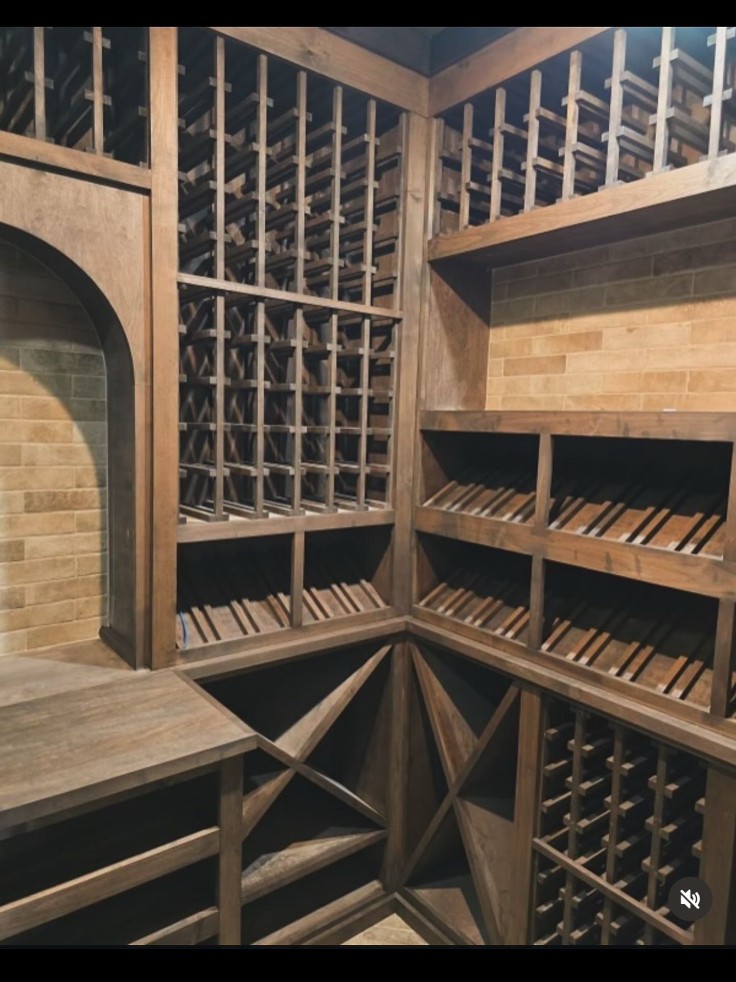 Wooden wine cellar with brick walls and various bottle storage racks.
