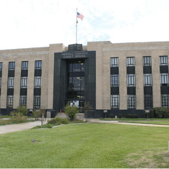 Orange County Courthouse building with a green lawn and American flag.
