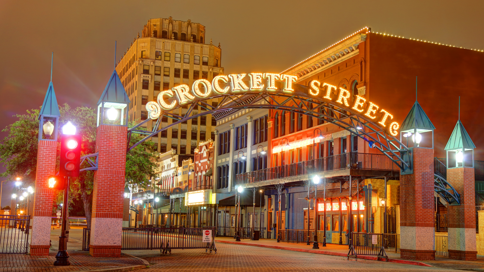 Night view of Crockett Street entrance in Beaumont, Texas, with illuminated sign and brick structures.