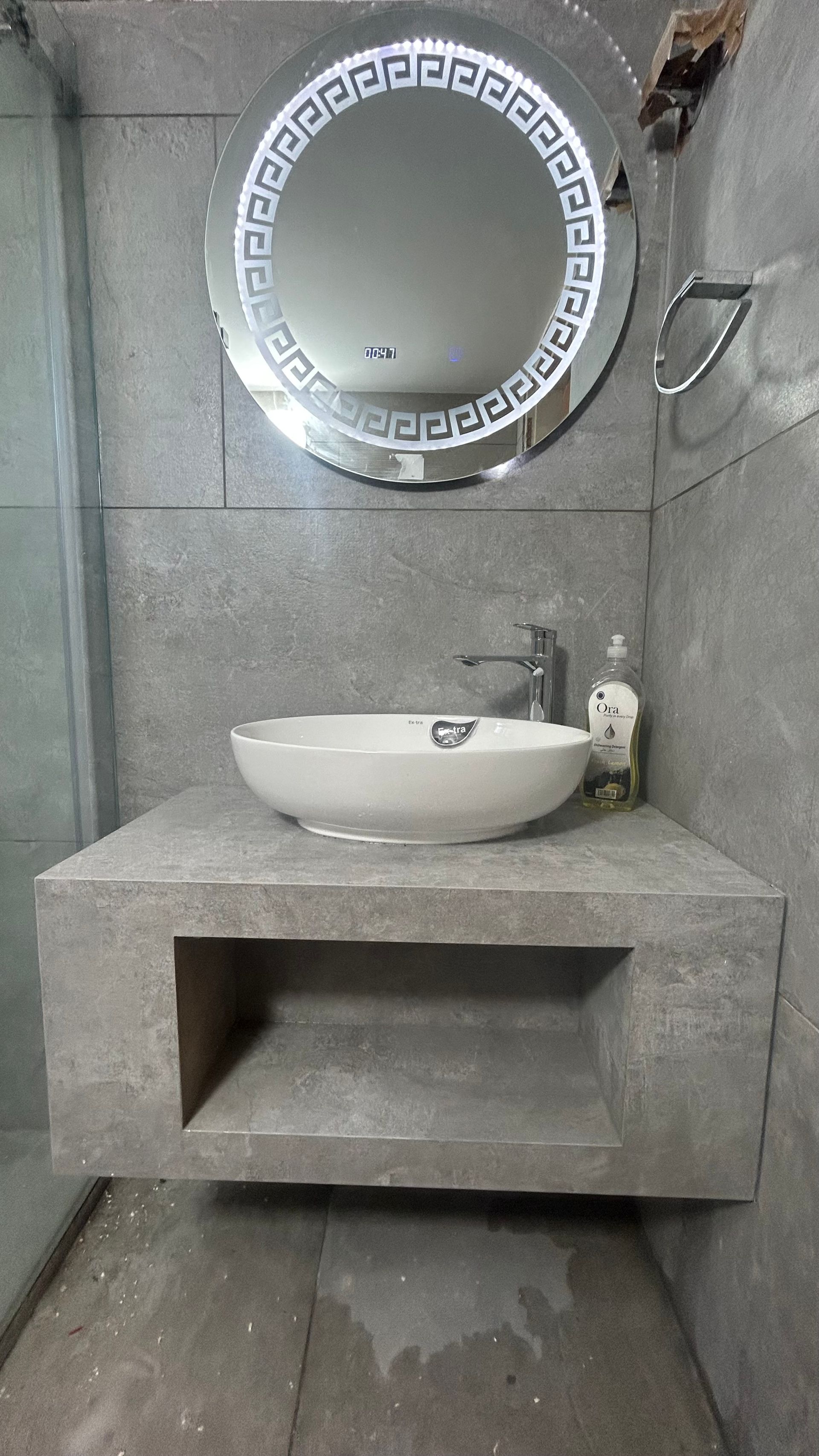 Bathroom sink with a round mirror and a grey stone counter.