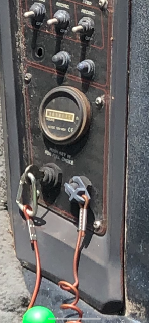 Panel with switches, gauge, and power connectors attached to a black machine, possibly a generator.