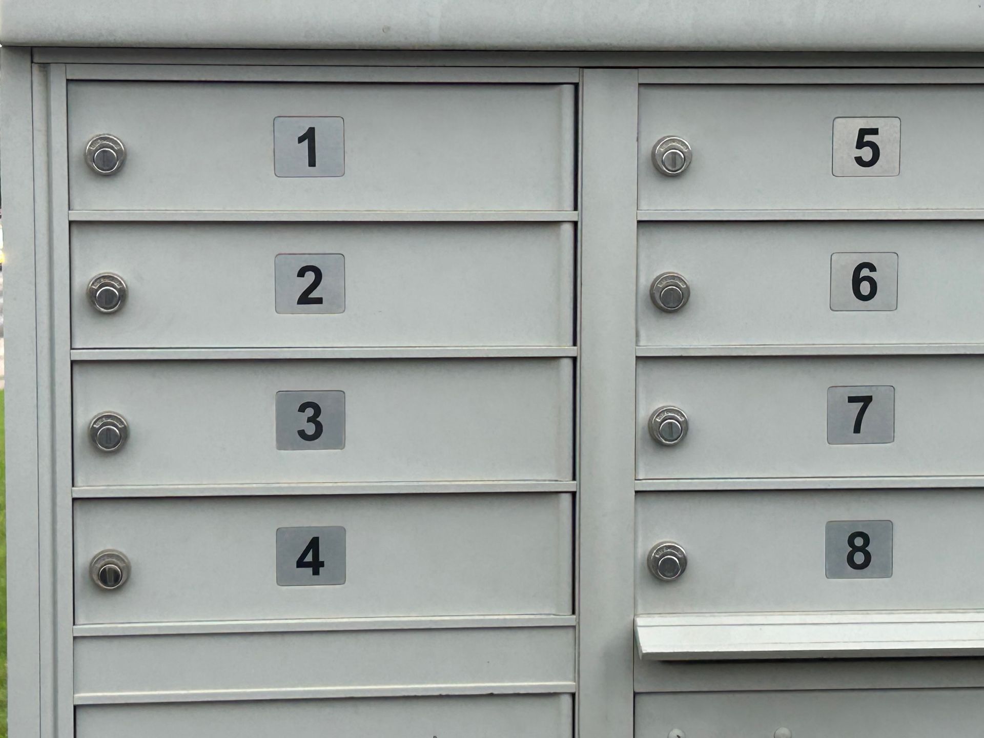 Mailboxes numbered 1-8. White, metal. Some have circular door handles.