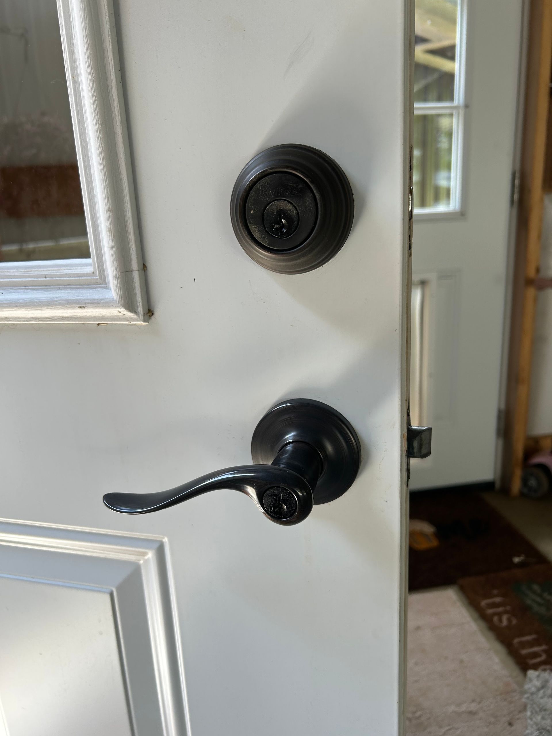 Black door lock and handle on a white door. The door leads to a room.