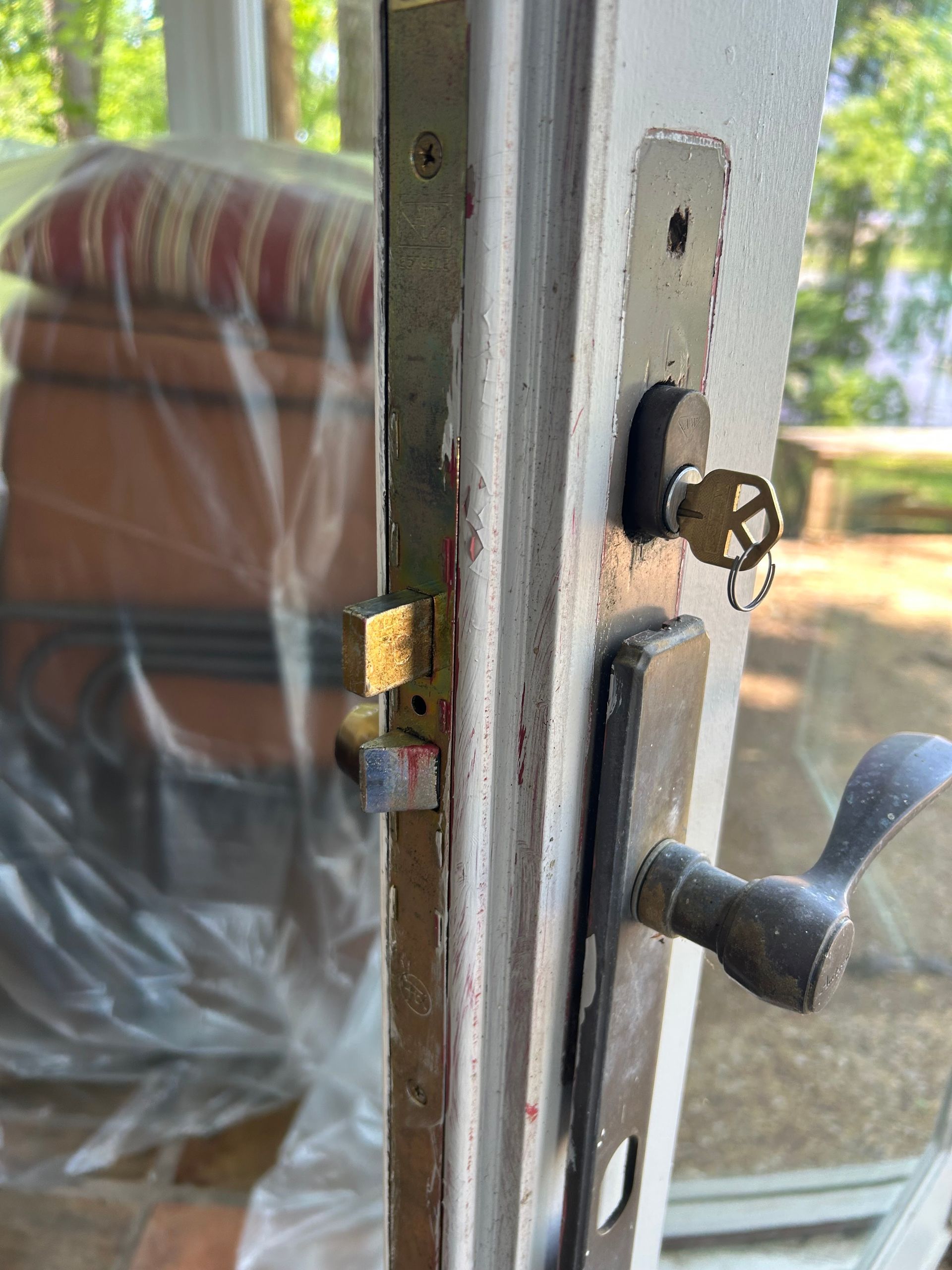 Close-up of a door lock with a key inserted. The door is slightly ajar, showing the mechanism and handle.