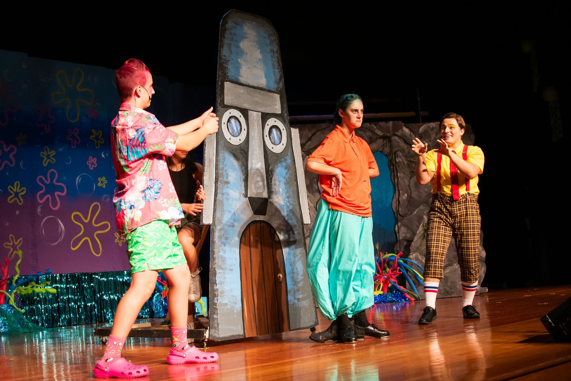 Actors on stage in colorful costumes during a play; SpongeBob SquarePants theme.