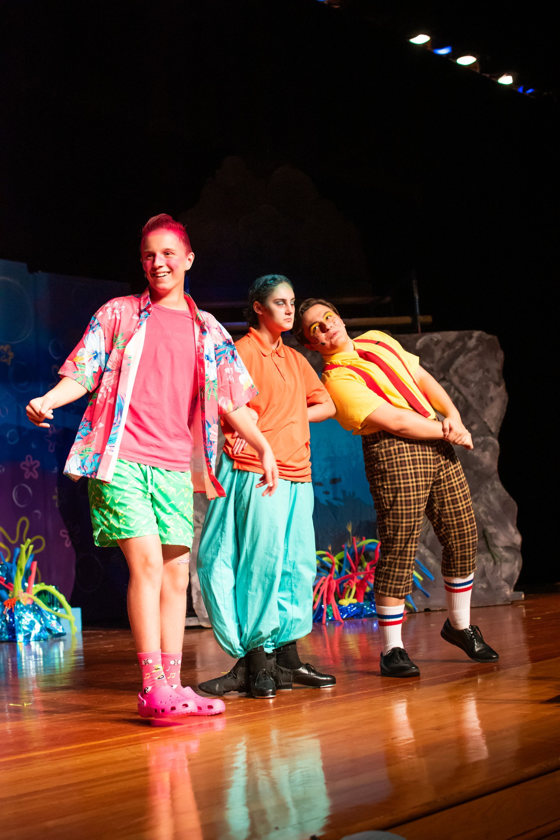 Three costumed actors on stage: SpongeBob, Patrick, and Squidward in a play.