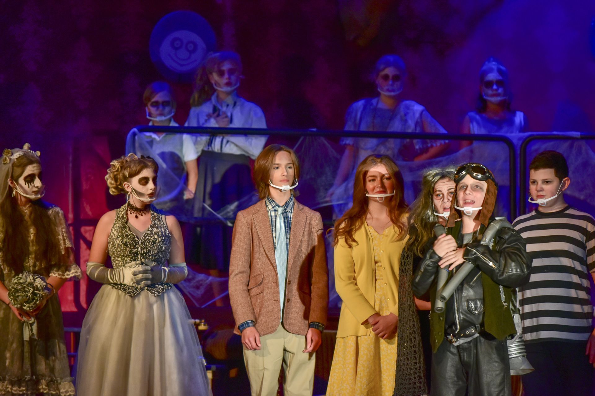 Group of costumed actors on stage; some with painted faces.