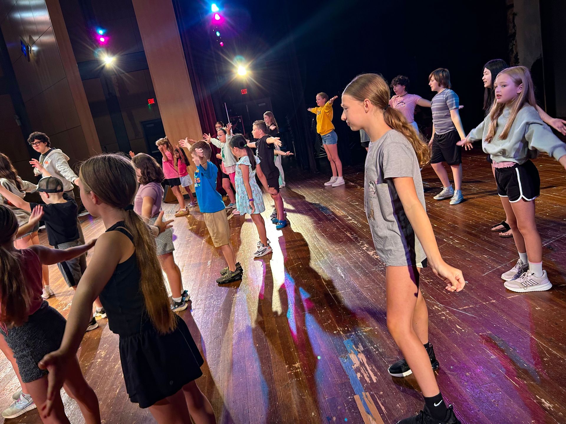 Group of young dancers on stage with colorful lights.