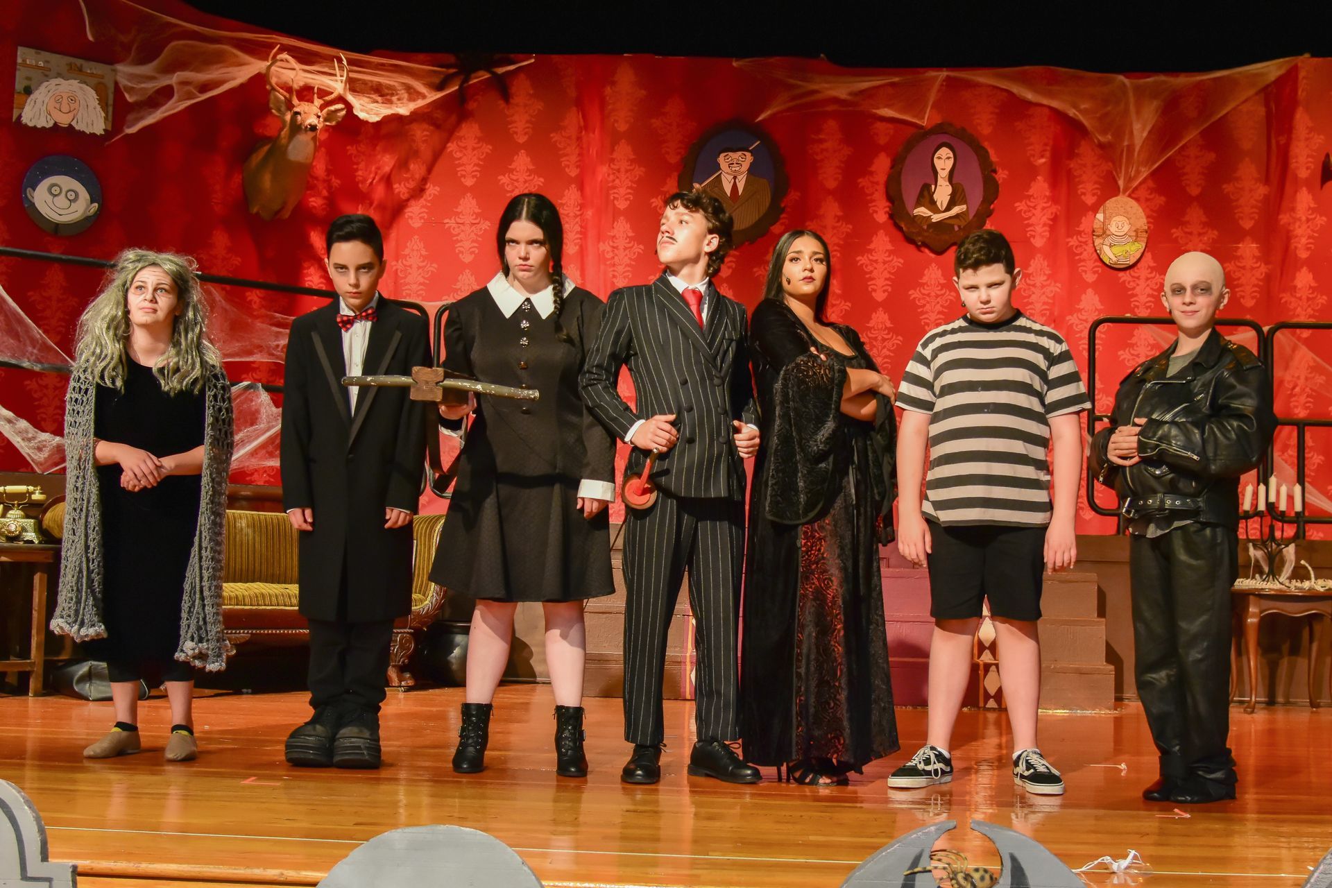 Cast of The Addams Family musical on stage, dressed in character costumes.