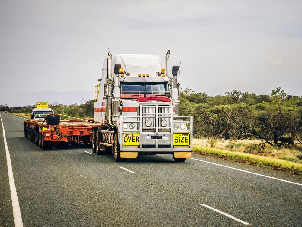 A Semi Truck Is Driving Down A Highway Next To A Trailer — Geisler Truck & Trailer Wheel Alignments In Pleystowe, QLD