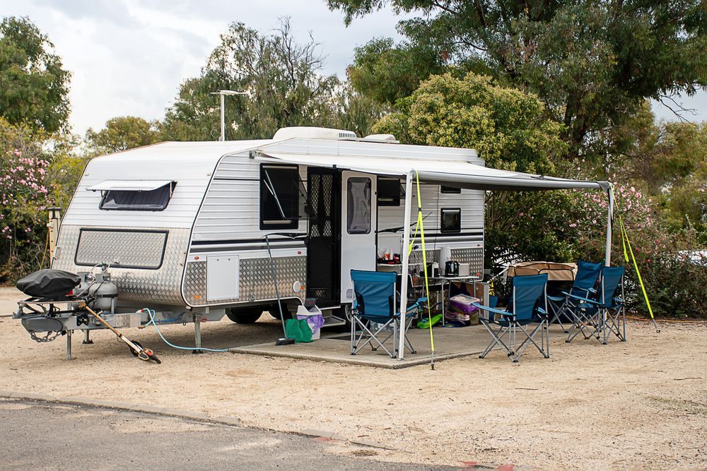A Caravan Is Parked In A Gravel Area With A Canopy And Chairs — Geisler Truck & Trailer Wheel Alignments In Pleystowe, QLD