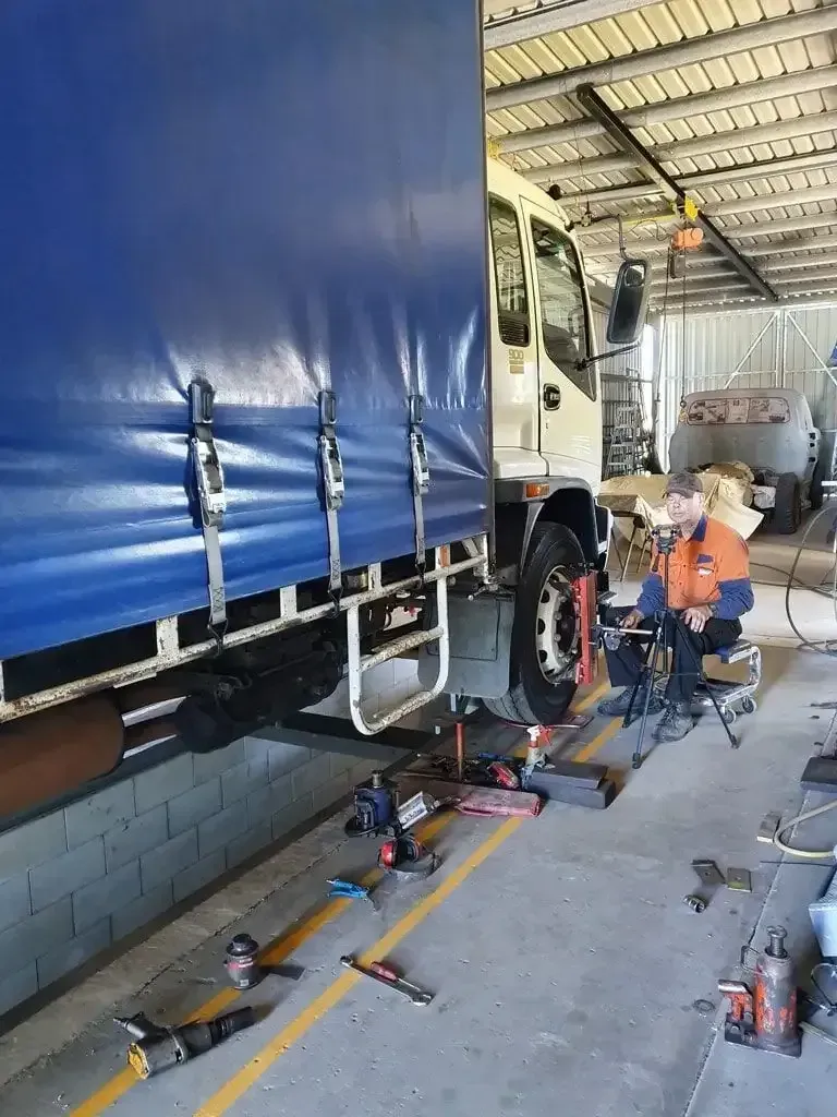 A Man Is Working On A Truck In A Garage — Geisler Truck & Trailer Wheel Alignments In Pleystowe, QLD