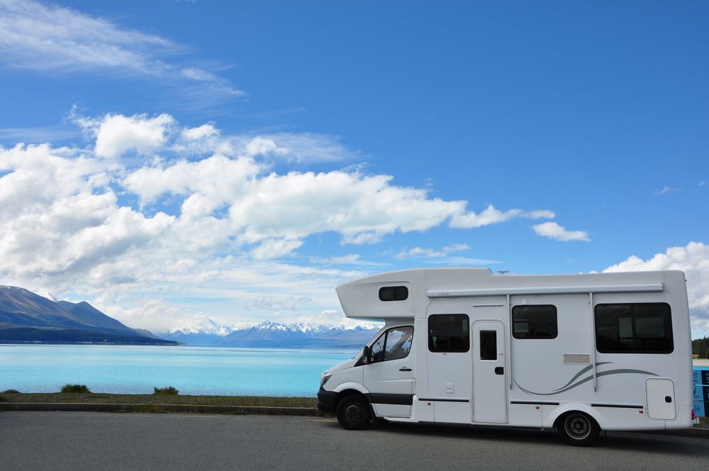A White Caravan Is Parked Next To A Lake With Mountains — Geisler Truck & Trailer Wheel Alignments In Marian, QLD