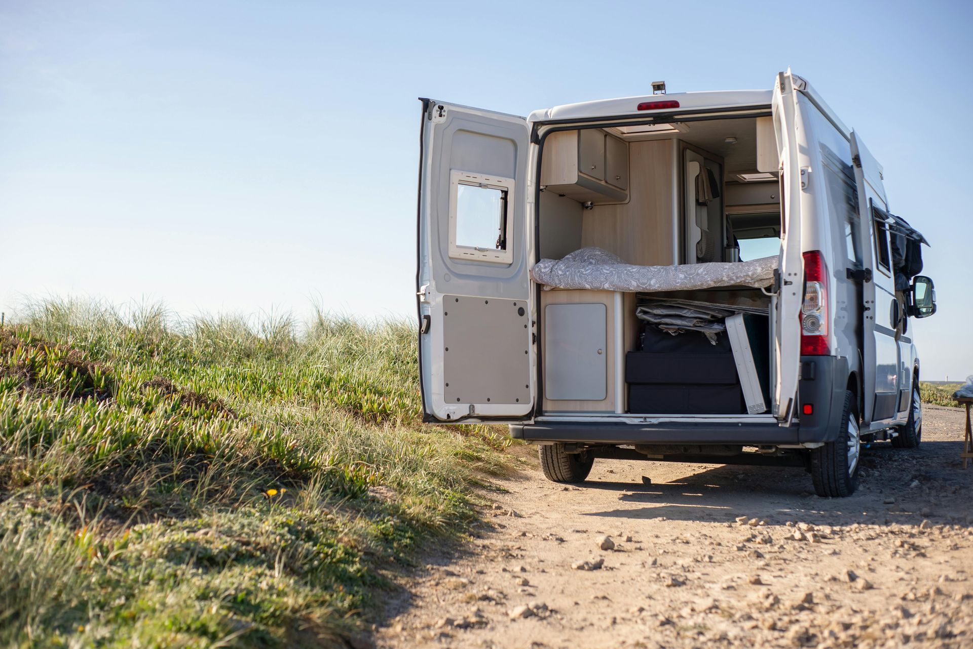 A camper van is parked on a dirt road with its doors open. — Geisler Truck & Trailer Wheel Alignments In Pleystowe, QLD