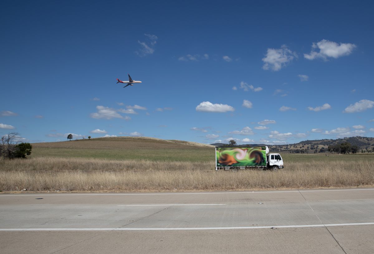 A Plane Is Flying Over A Field With A Truck In The Foreground — Geisler Truck & Trailer Wheel Alignments In Mackay, QLD