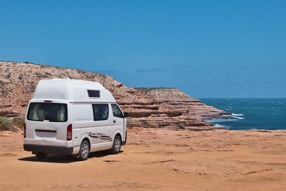 A White Van Is Parked On A Sandy Beach Near The Ocean — Geisler Truck & Trailer Wheel Alignments In Nebo, QLD