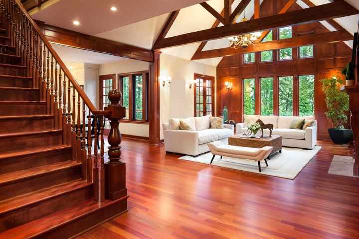 Wooden staircase leads to a spacious living room with white sofas, a coffee table, and large windows.