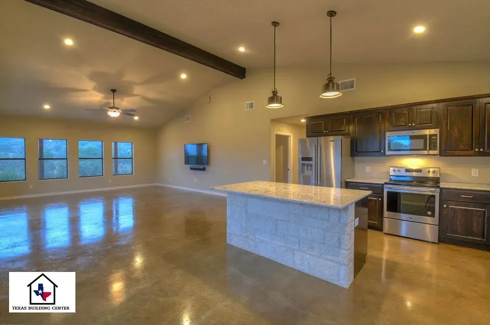 Spacious open-concept kitchen and living area with stained concrete floors, stainless steel appliances, and a large island.
