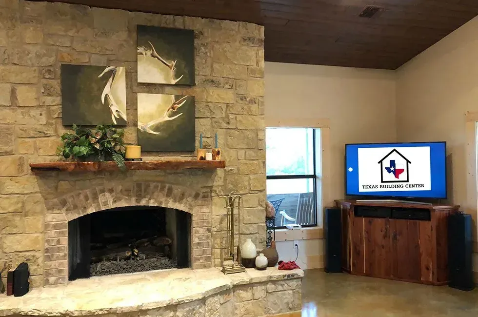 Living room with stone fireplace, artwork, TV on wooden cabinet, and speakers.
